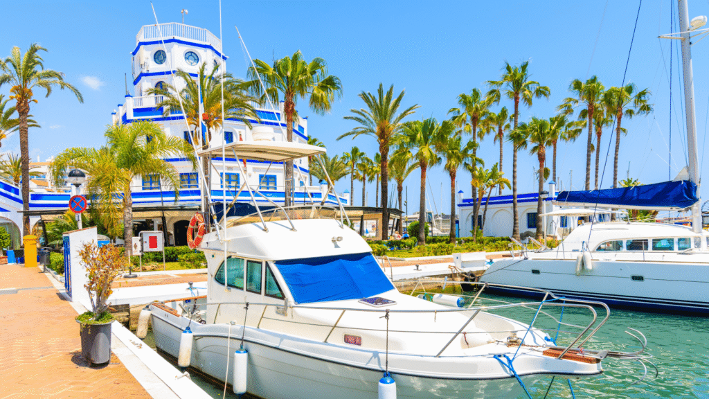 Luxury marina in Estepona, Costa del Sol — yachts docked at Puerto Deportivo surrounded by palm trees and white-blue Mediterranean architecture-Quintessentia Property Advisors