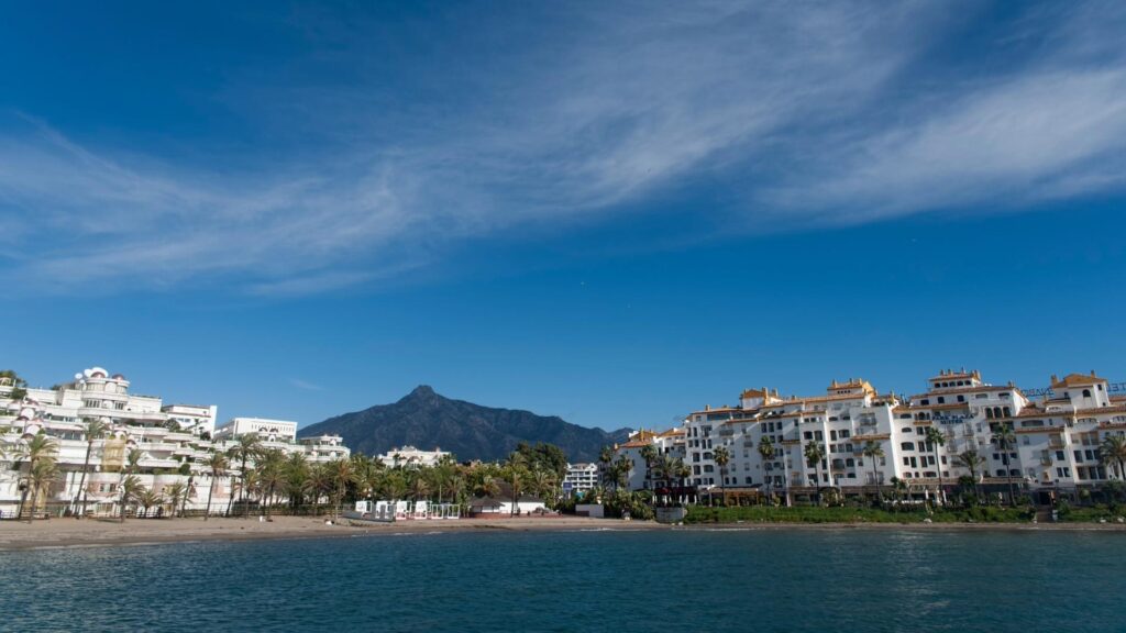 Beachfront residential buildings in Nueva Andalucia, Marbella, with mountain views and blue skies