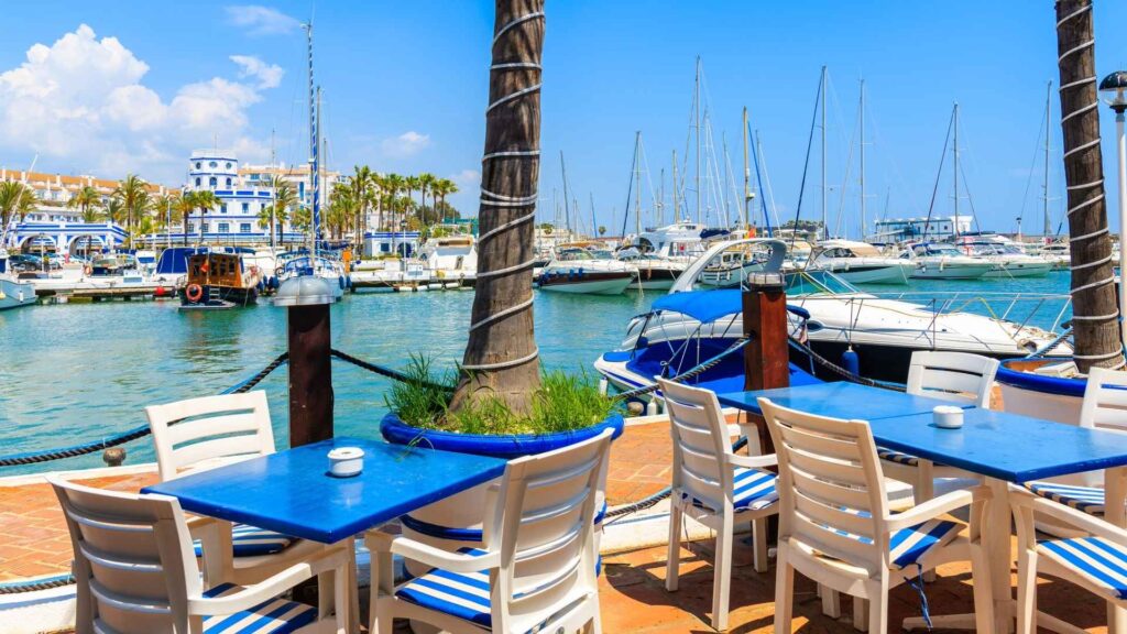 Colorful marina in Estepona with waterfront cafés, boats, and yachts — a popular family-friendly neighborhood on the Costa del Sol within the Estepona best areas.