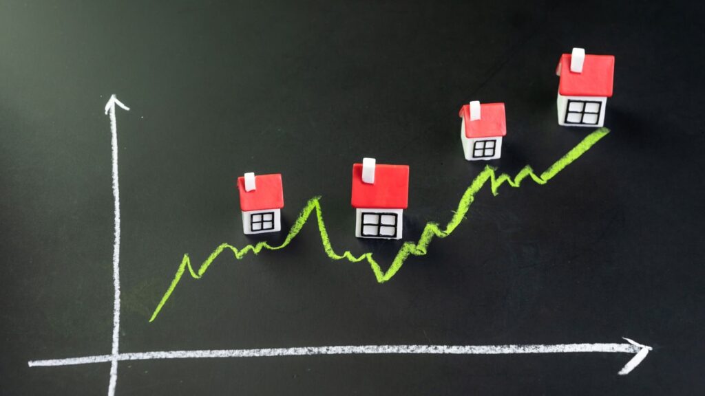 Rising property prices in Nueva Andalucía shown with miniature houses on an upward graph representing real estate market growth