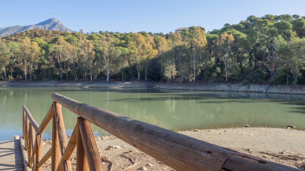 Scenic view of lake and mountains near Nueva Andalucía, Marbella, surrounded by pine forests — popular area for luxury villas