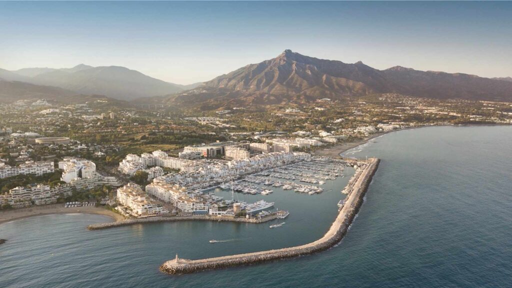 Aerial view of Puerto Banús marina and luxury neighborhoods in Nueva Andalucía, Marbella, with La Concha mountain in the background.
