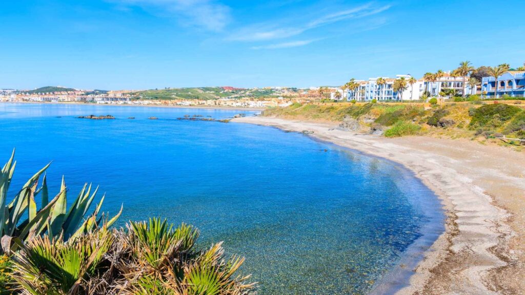 Beautiful beachfront in Estepona with turquoise waters, golden sand, and modern coastal properties along the Costa del Sol