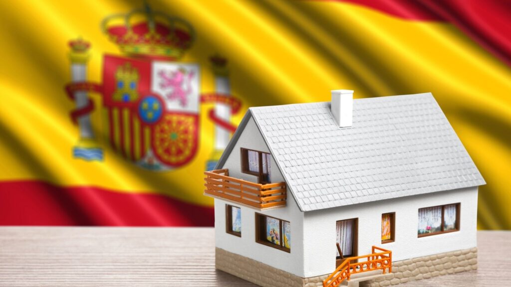 Model house in front of Spanish flag representing property ownership for non-residents in Spain.