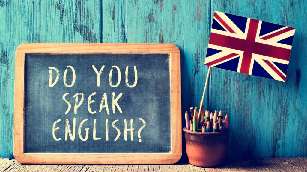 Chalkboard with the text ‘Do you speak English?’ next to a pot of pencils and a small Union Jack flag.