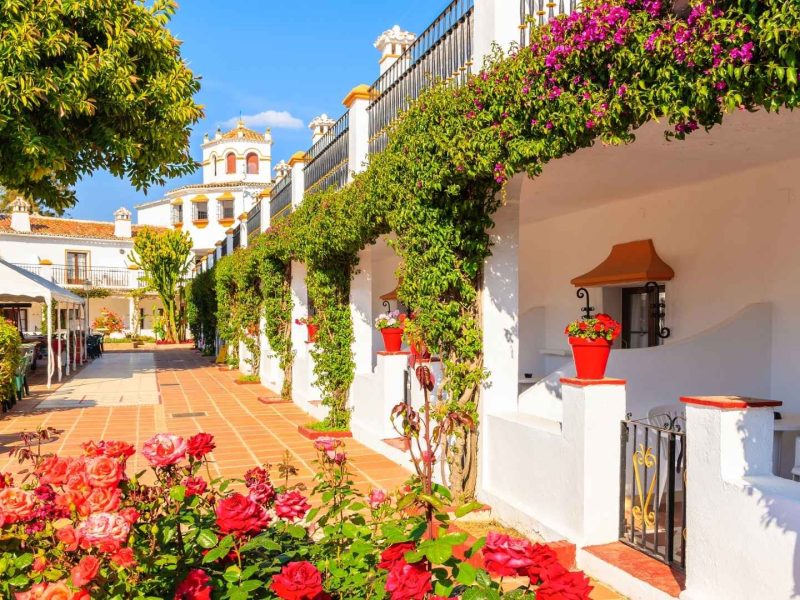 Charming traditional Andalusian street in Marbella, Spain, with whitewashed houses, flowers, and Mediterranean-style architecture, showcasing the character of Marbella’s top property areas.