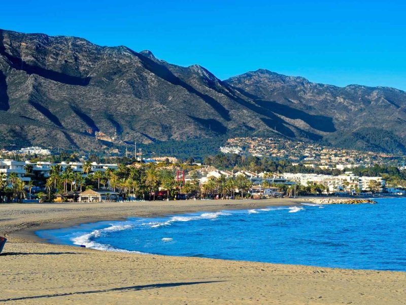 Beautiful beach and coastal skyline in Nueva Andalucía with mountains in the background, showcasing area for new property developments in Marbella