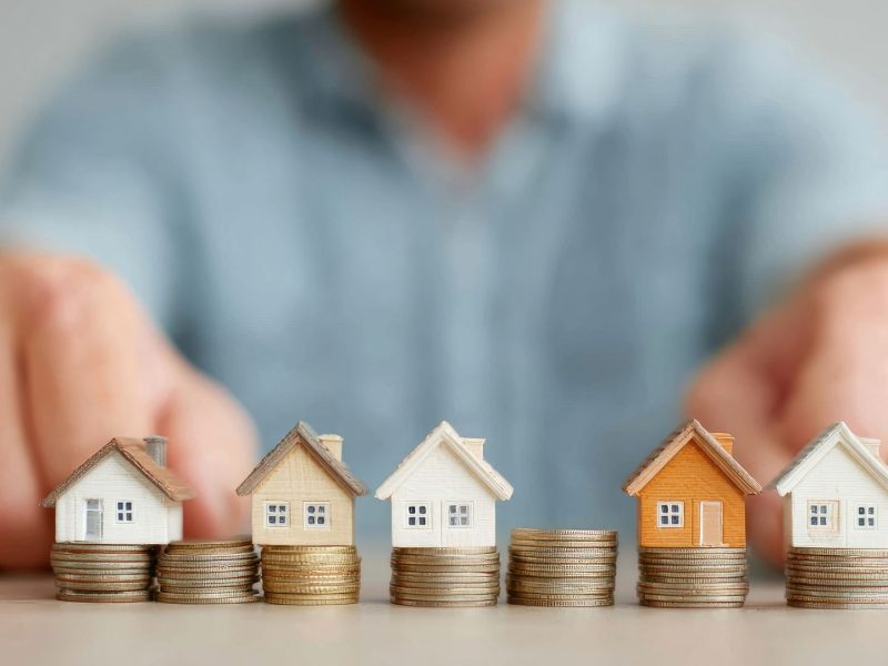 Miniature houses on stacked coins representing rental yields and property investment returns in Nueva Andalucía, Marbella