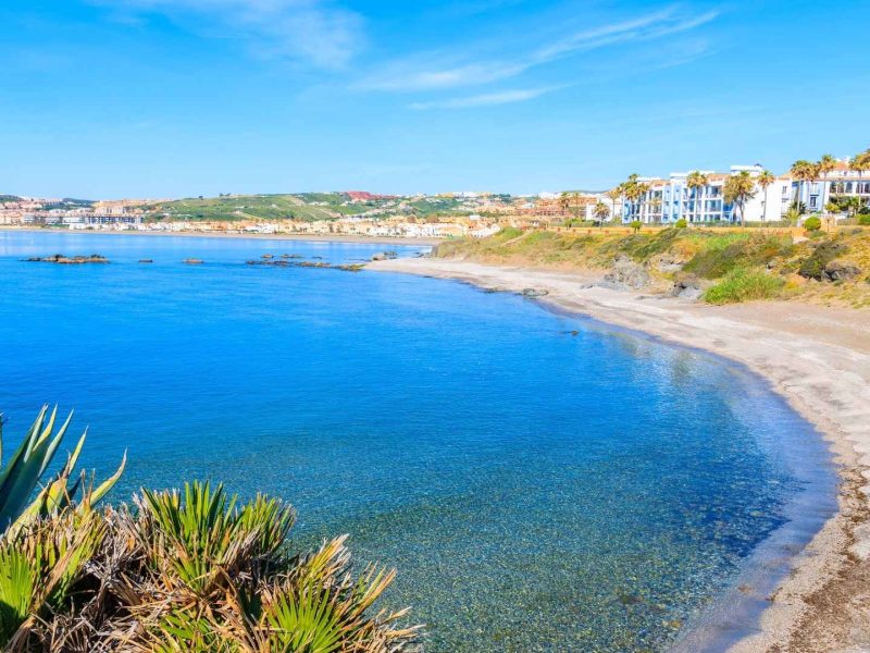 Beautiful beachfront in Estepona with turquoise waters, golden sand, and modern coastal properties along the Costa del Sol