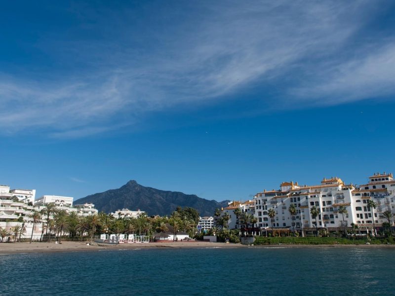 Beachfront residential buildings in Nueva Andalucia, Marbella, with mountain views and blue skies